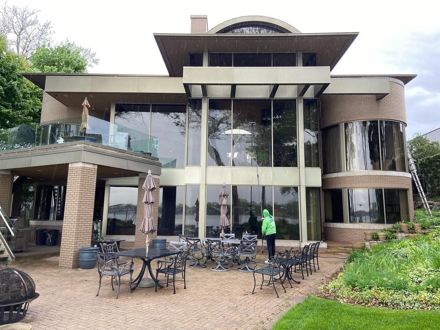 A Glass Guru technician cleaning the glass wall of a lakefront home in West Bloomfield, Michigan