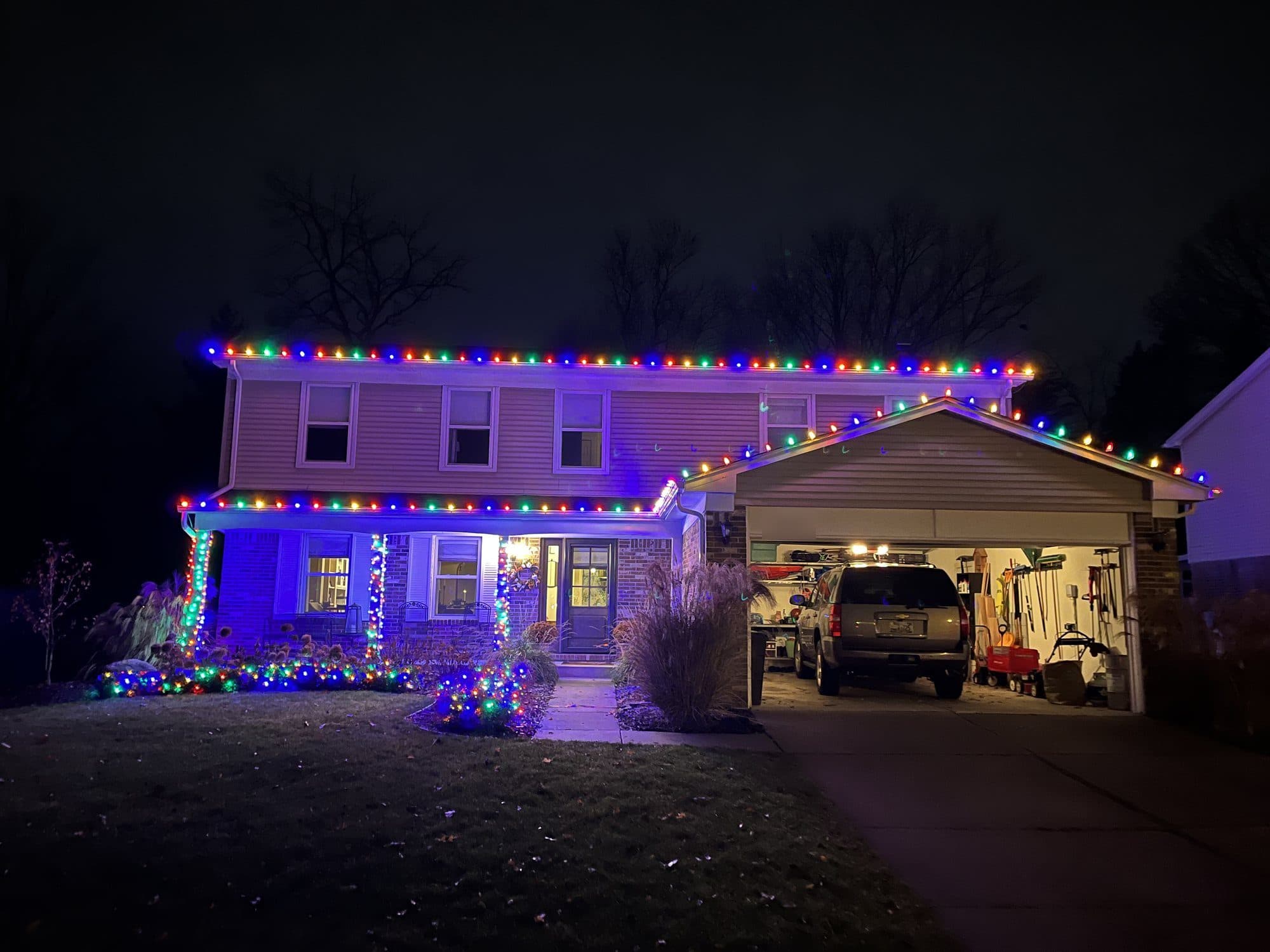 A two-story home with multicolor bulbs along the rooflines and over the garage