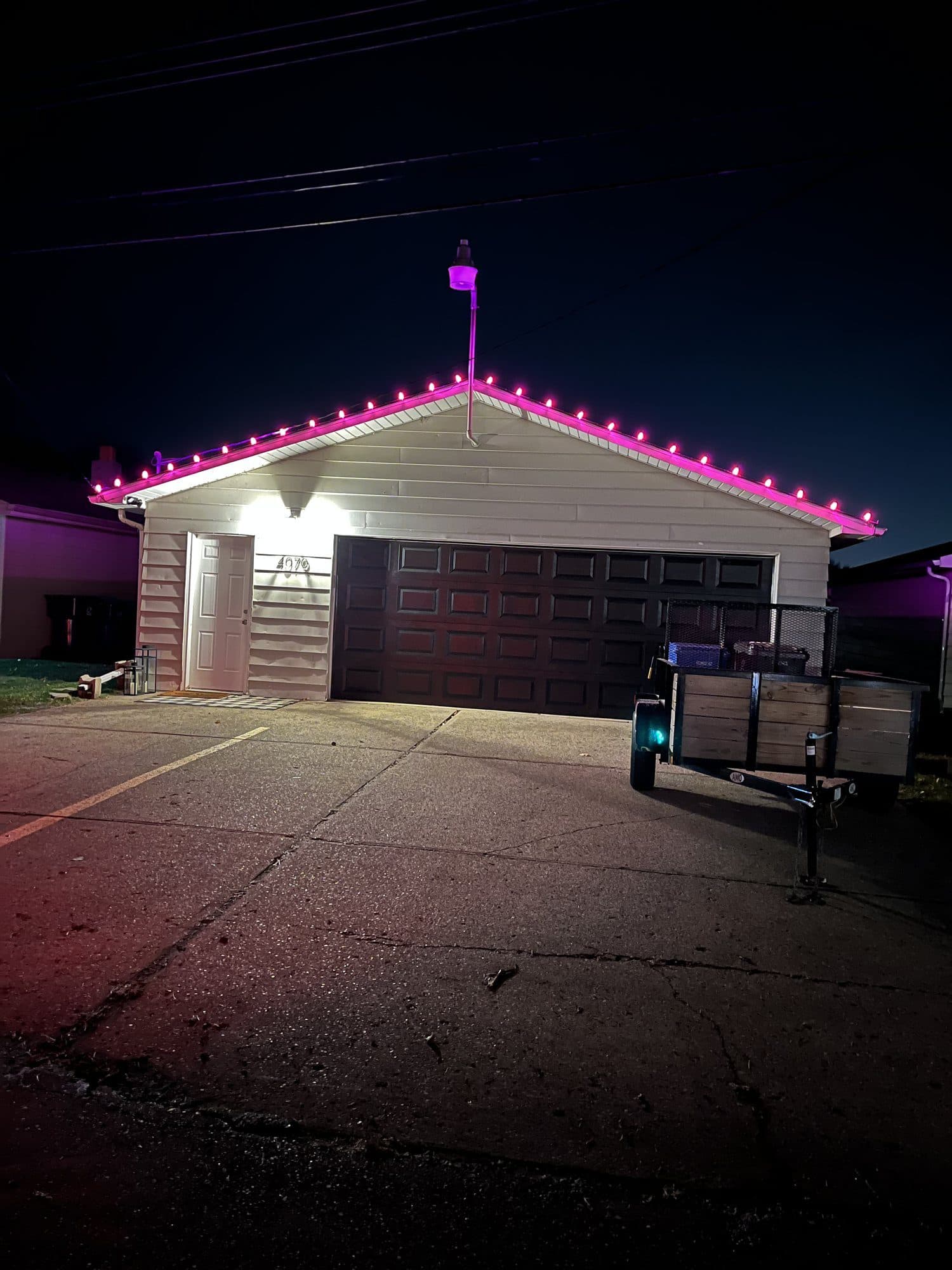 A garage roofline outlined in pink bulbs at night